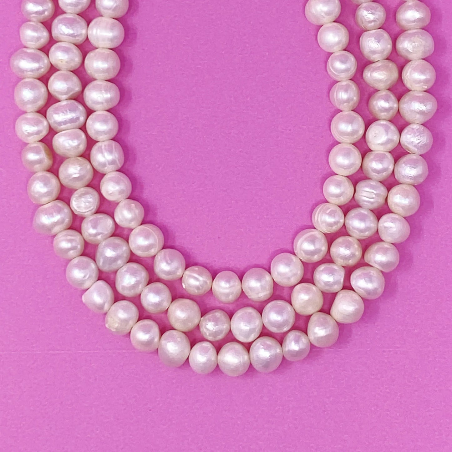 Three Strands Freshwater Pearl Necklace on a pink background