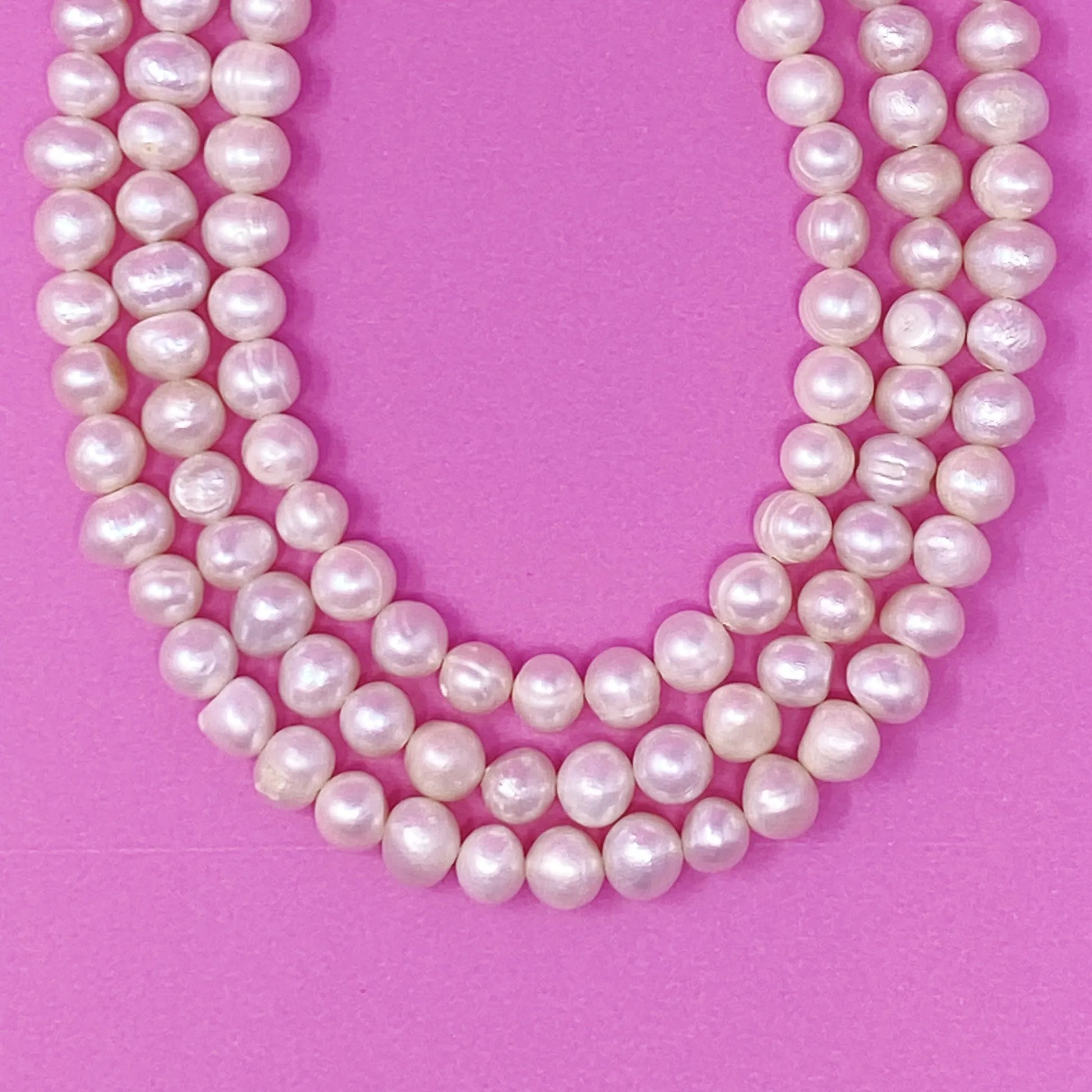 Three Strands Freshwater Pearl Necklace on a pink background
